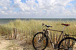 Ein Fahrrad lehnt an einem Zaun am Strand