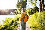 Eine Frau steht mit einem Rucksack auf einem Weg und schaut auf einen See.