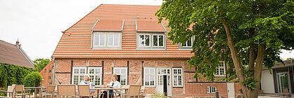 Zwei Personen sitzen vor dem "Seeminarhaus" - einer Tagungsstätte auf Gut Groß Zecher.  - zum Artikel 'Schleswig-Holstein meets business'