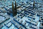 Detailansicht des bronzenen Stadtmodells von Lübeck mit hervorgehobenen Miniatur-Gebäuden und glänzenden Kirchturmspitzen.