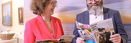 Dr. Bettina Bunge und Claus Ruhe Madsen halten lachend das Magazin "Ganz weit oben" in der Hand.  - zum Artikel '„Ganz weit oben“ – Das neue Magazin zum Reiseland Schleswig-Holstein '