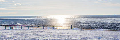 Verschneiter und Vereister Nordseestrand. Die Sonne spiegelt sich im Meer. - zum Artikel 'Buchungslage für Weihnachten und den Jahreswechsel 2022/23 in Schleswig-Holstein '